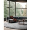 Curved gray sofa and armchair against of floor to ceiling window. Minimalist interior design of modern living room with round coffee table on grey rug.