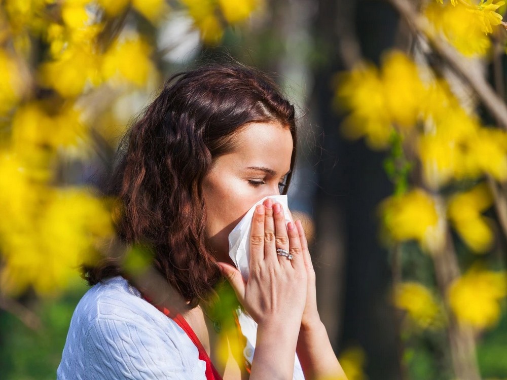 Žena s kapesníkem u nosu během jarní pylové sezóny