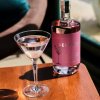 Na dřevěném stole nalitý koktejl z lahve Seekers Lychee Martini