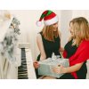 Dve ženy pri vianočne ozdobenom klavíri – elegantná atmosféra doplnená červeno-zelenou mikulášskou čiapkou