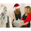 Dve ženy pri klavíri počas Vianoc – darček v rukách a červeno-čierna mikulášska čiapka s bielym lemom a brmbolcom
