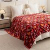 Mäkká vianočná prikrývka s červeným motívom rozprestretá na posteli – ideálna ako deka aj ako ozdobná prehoď