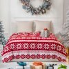 Červená vianočná deka s bielymi vločkami v zimnej výzdobe – útulný doplnok pre sviatočné obdobie