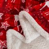 Detail červenej deky s bielym barančekom a vianočným vzorom sobov a hviezd – hebká a teplá zimná prikrývka