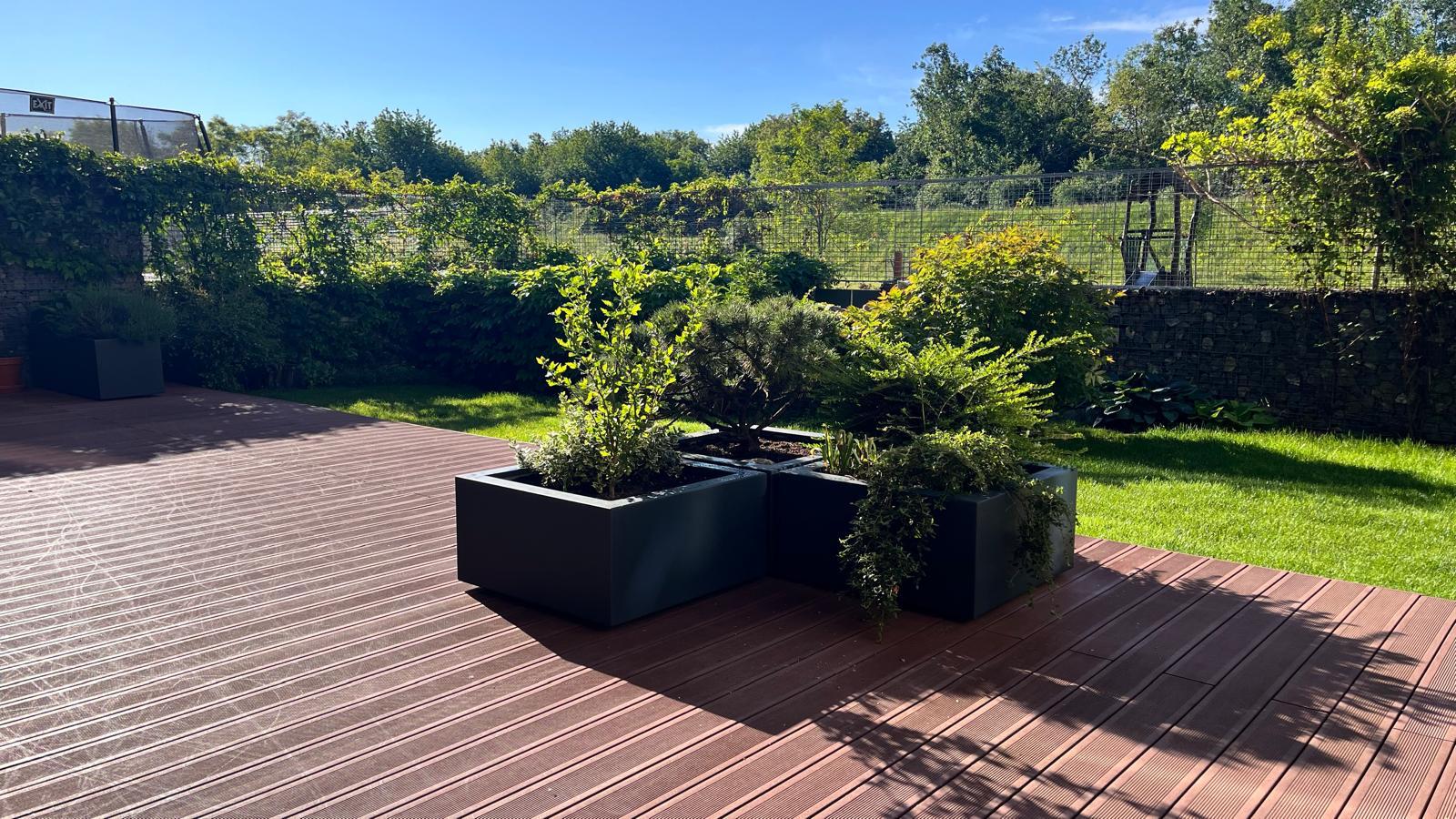 Pohled na terasu s květináči a okolní zahradou