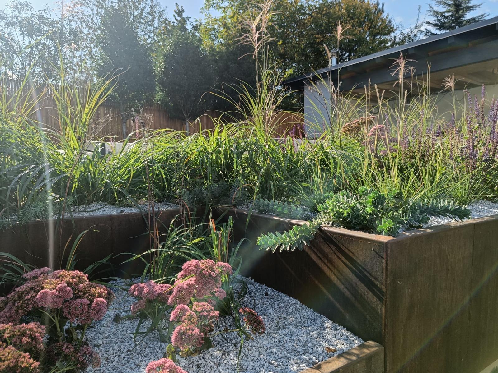 Zahrada s cortenovým květináčem a členitým terénem