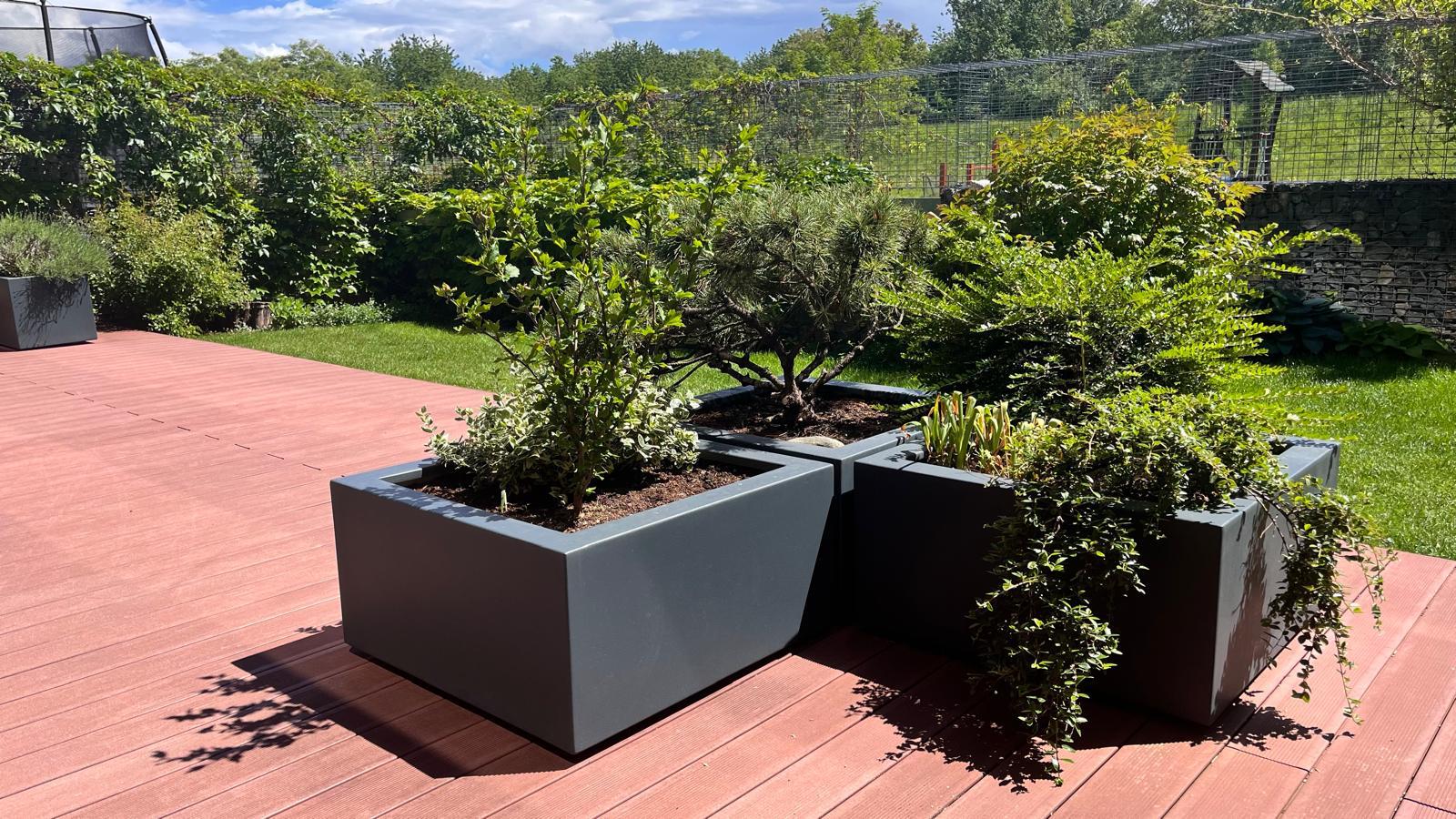Zeleň v květináčích z lakovaného hliníku v městské zahradě