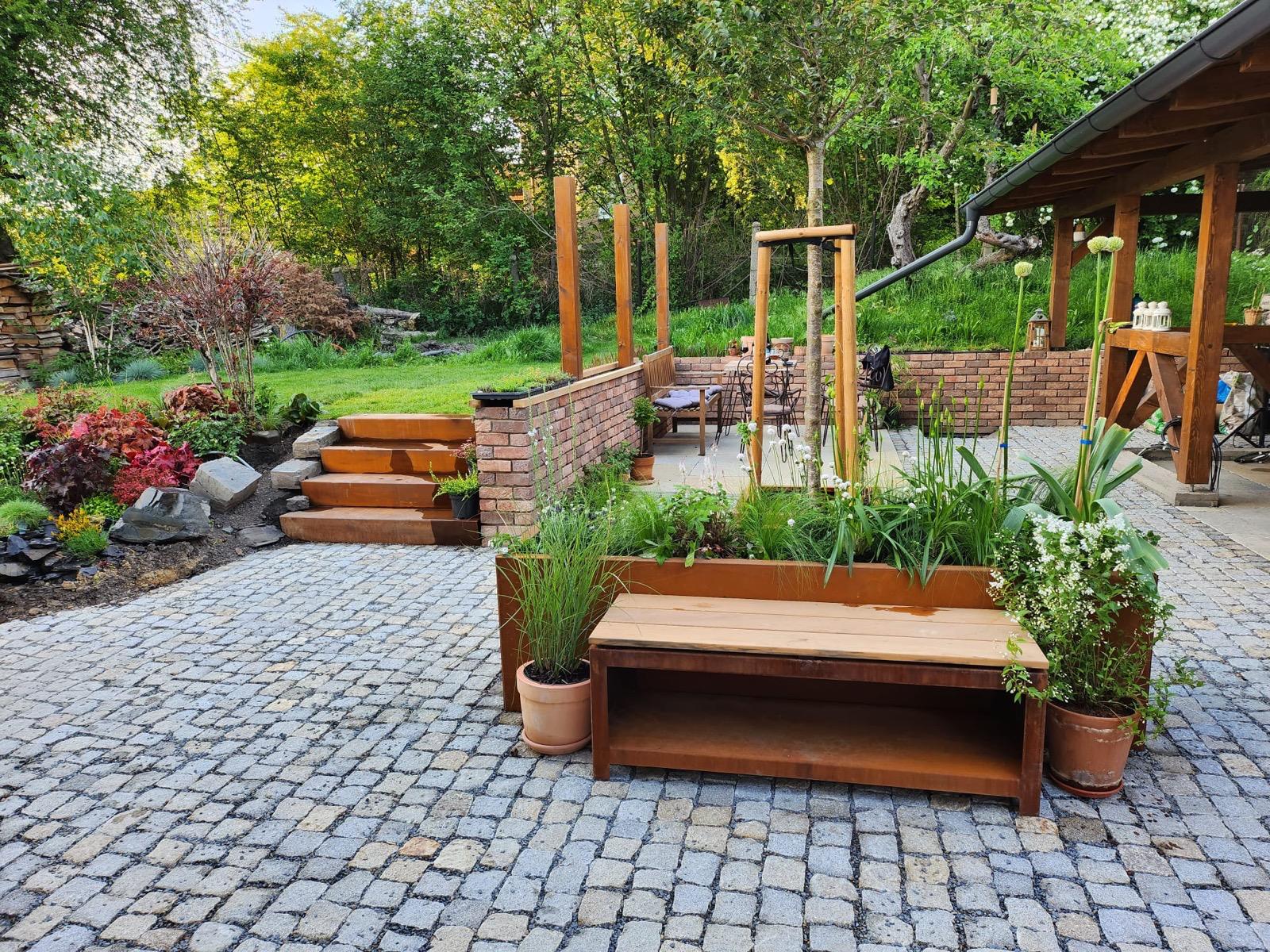 Cortenový květináč na rozhraní dlažby a štěrku