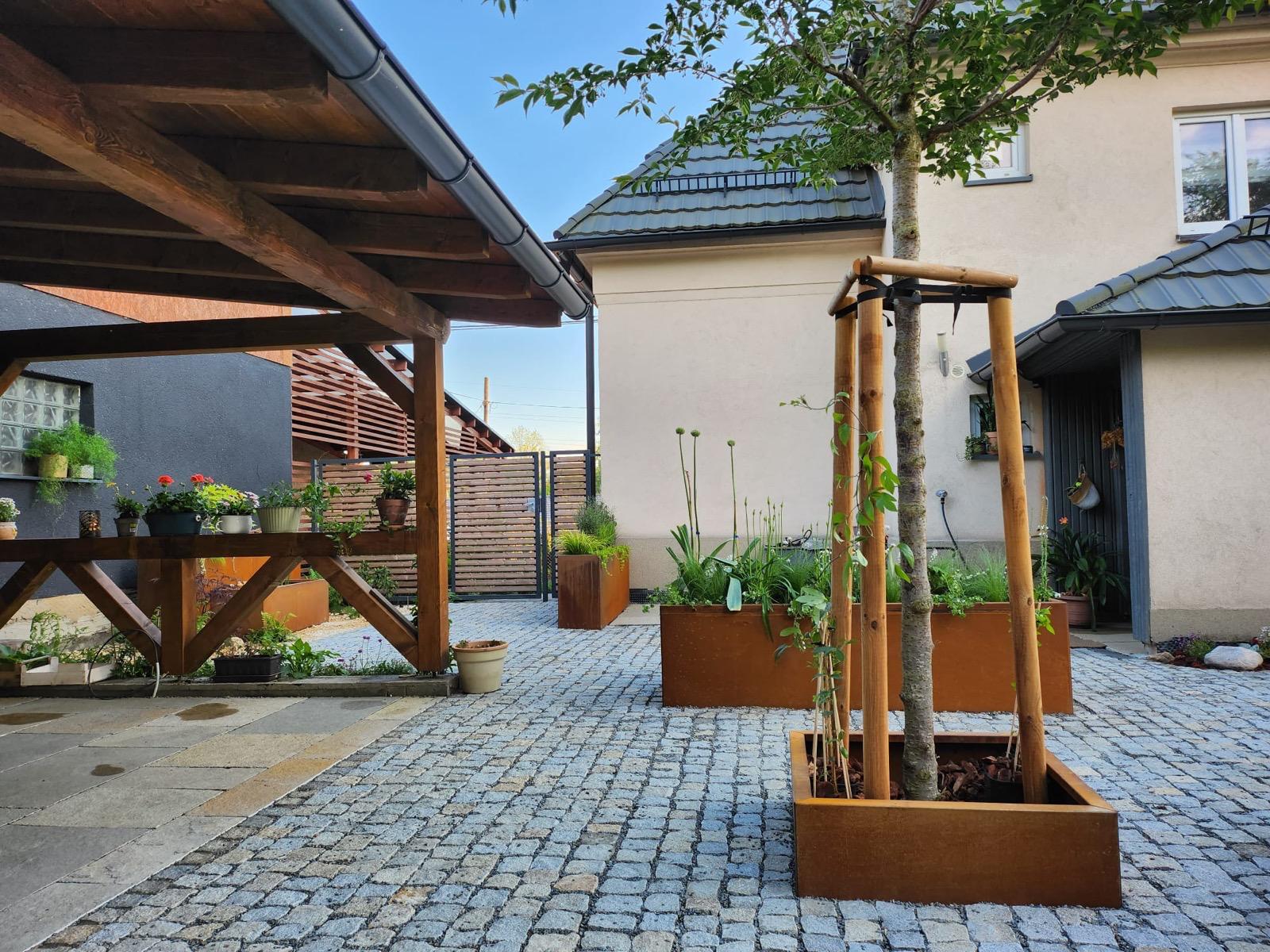 Cortenový květináč u cihlové zídky a dlažby