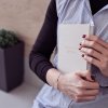 Žena drží denní produktivní diář v náručí, jemná lifestyle scéna vhodná pro inspiraci k vědomému plánování