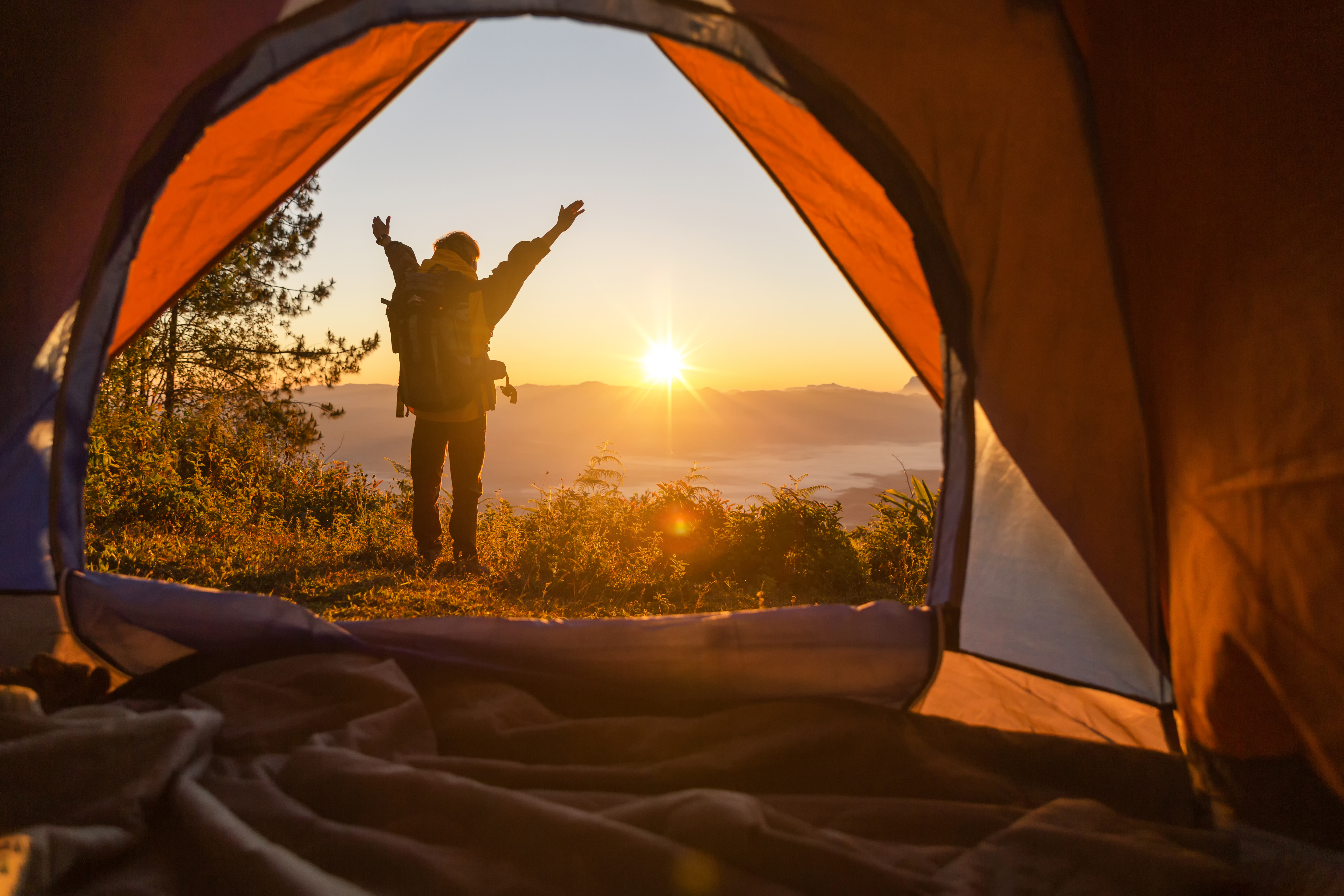 hiker-stand-camping-front-orange-tent-backpack-mountains