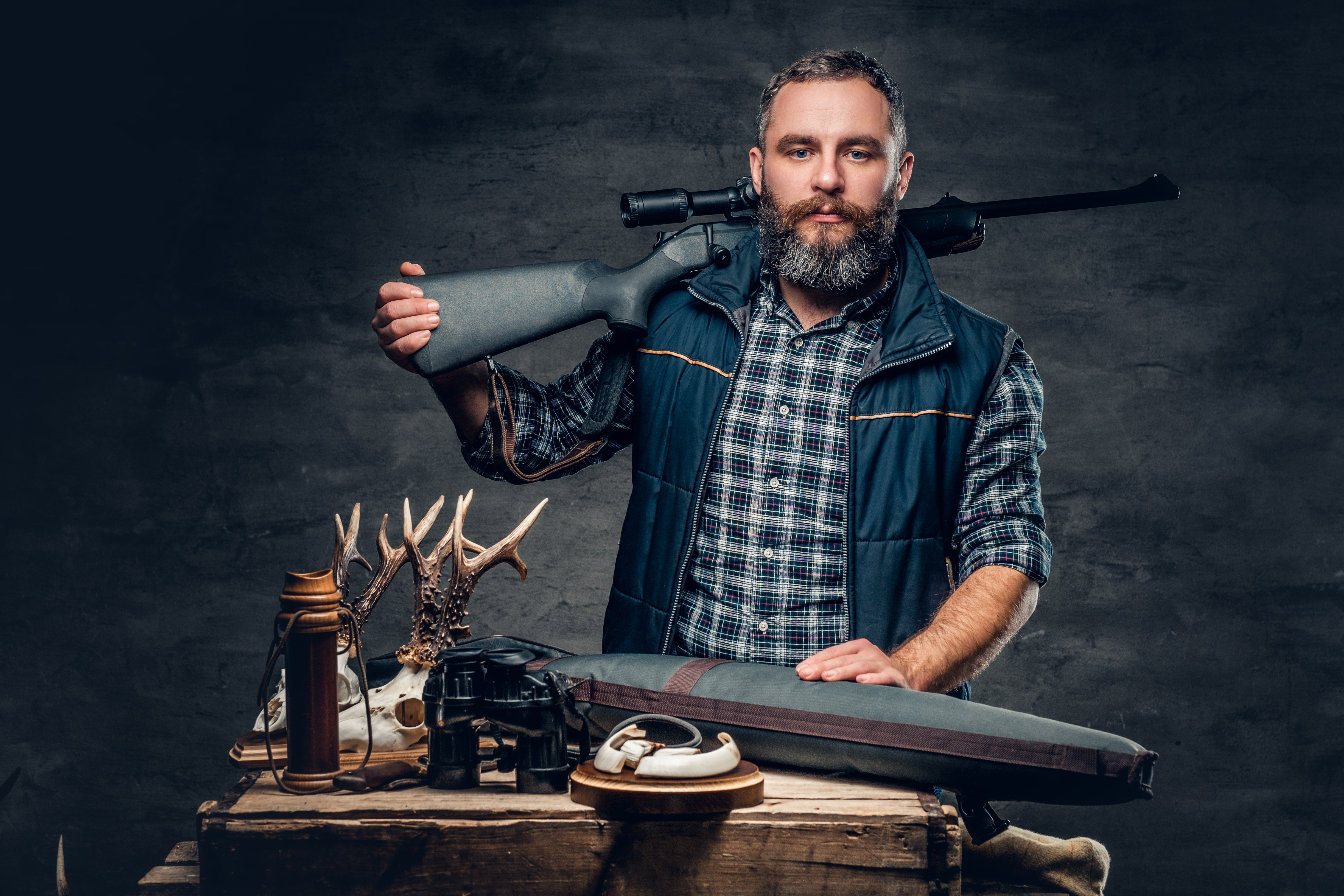 studio-portrait-bearded-modern-hunter-with-his-trophy-holds-rifle