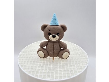 Roztomilá figúrka hnedého medvedíka s modrou bodkovanou čiapočkou, ideálna dekorácia na oslavu pre chlapca.