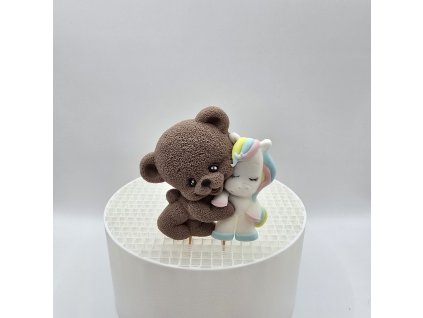 Dekorácia na tortu zobrazujúca hnedého macka v objatí s malým jednorožcom.