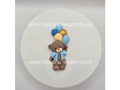 Cukrová figúrka hnedého macka s modrými balónikmi a modrou mašľou pod krkom.