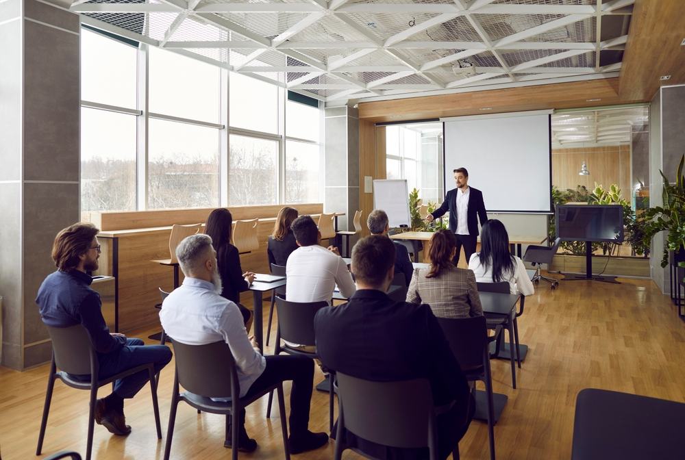 Profesional predstavuje PPC stratégiu skupine kolegov, zdôrazňujúc kľúčové informácie a stratégie na obrazovke počas stretnutia.