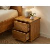 Noční stolek Mega Supra z masivu borovice s otevřenými zásuvkami vedle postele
