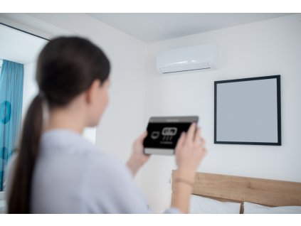 woman turning air conditioner using tablet