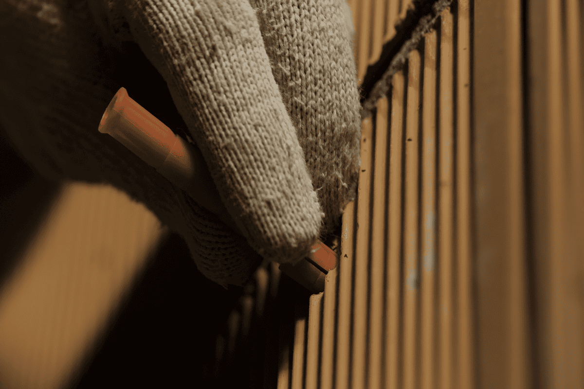 Ručné vkladanie hmoždinky v pracovných rukaviciach do vyvŕtanej diery v tehle