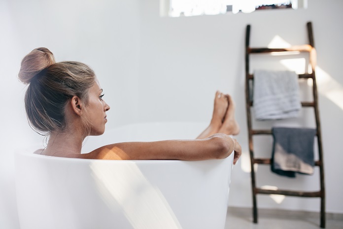 young-woman-lying-in-bathtub-and-looking-away-PQ5VNTV