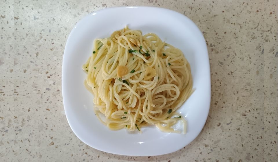 Naservírované spaghetti aglio, olio e peperoncino, ozdobené petrželkou.