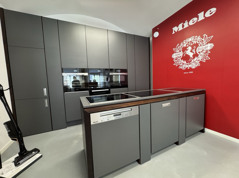Vestavná kuchyně Miele s brandovou červenou stěnou v showroomu