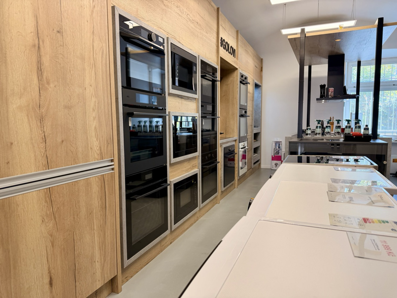 Showroom prodejny — vystavené vestavné trouby v dubové kuchyni
