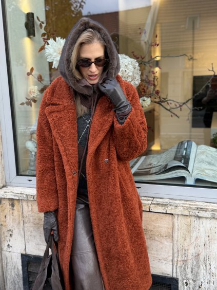 Oranžový teddy kabát v dlhom strihu na žene s hnedými doplnkami.
