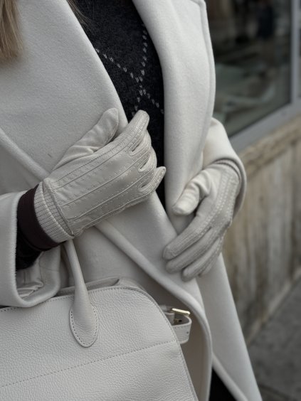 Krémové dámske rukavice z viskózy a kože pri elegantnom zimnom kabáte.