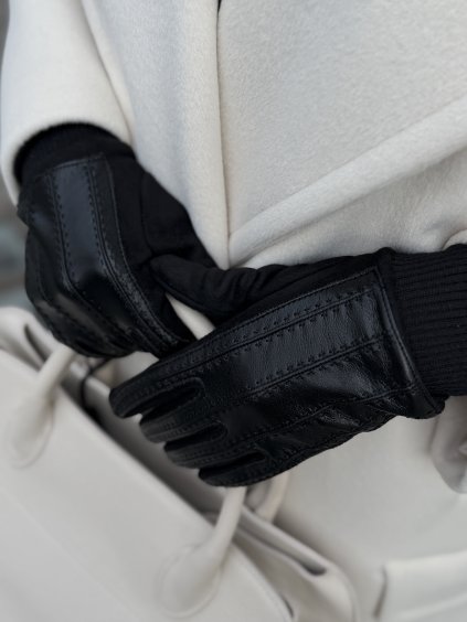 Čierne kožené dámske rukavice so šitými detailmi pri zimnom kabáte.