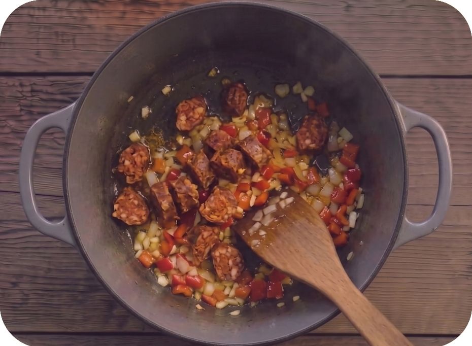 Hrniec, v ktorom sa restuje nakrájaná cibuľa, cesnak a paprika a chorizo