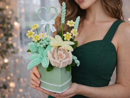 Žena v tmavě zelených šatech drží mentolový flower box s krémovými a mentolovými květy z modelovacích drátků, zdobený zeleným srdíčkem.
