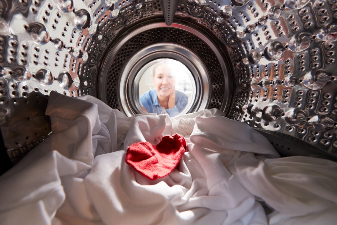 woman-looking-inside-washing-machine-with-red-sock-F82LP93