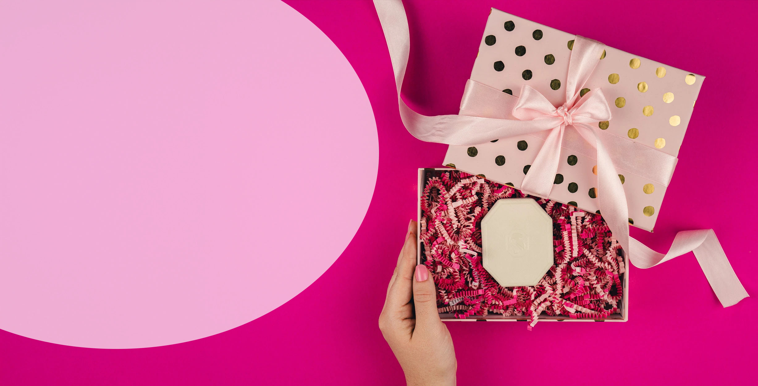 Růžová papírová výplň v poštovní krabici s růžovým produktem na modrém pozadí