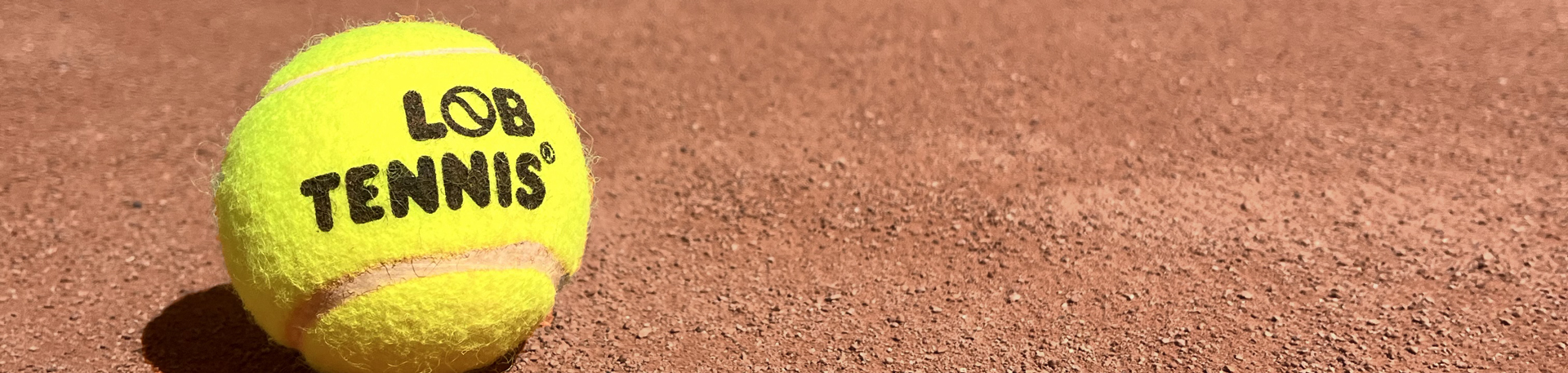 Tenisový míček LobSport na antukovém kurtu