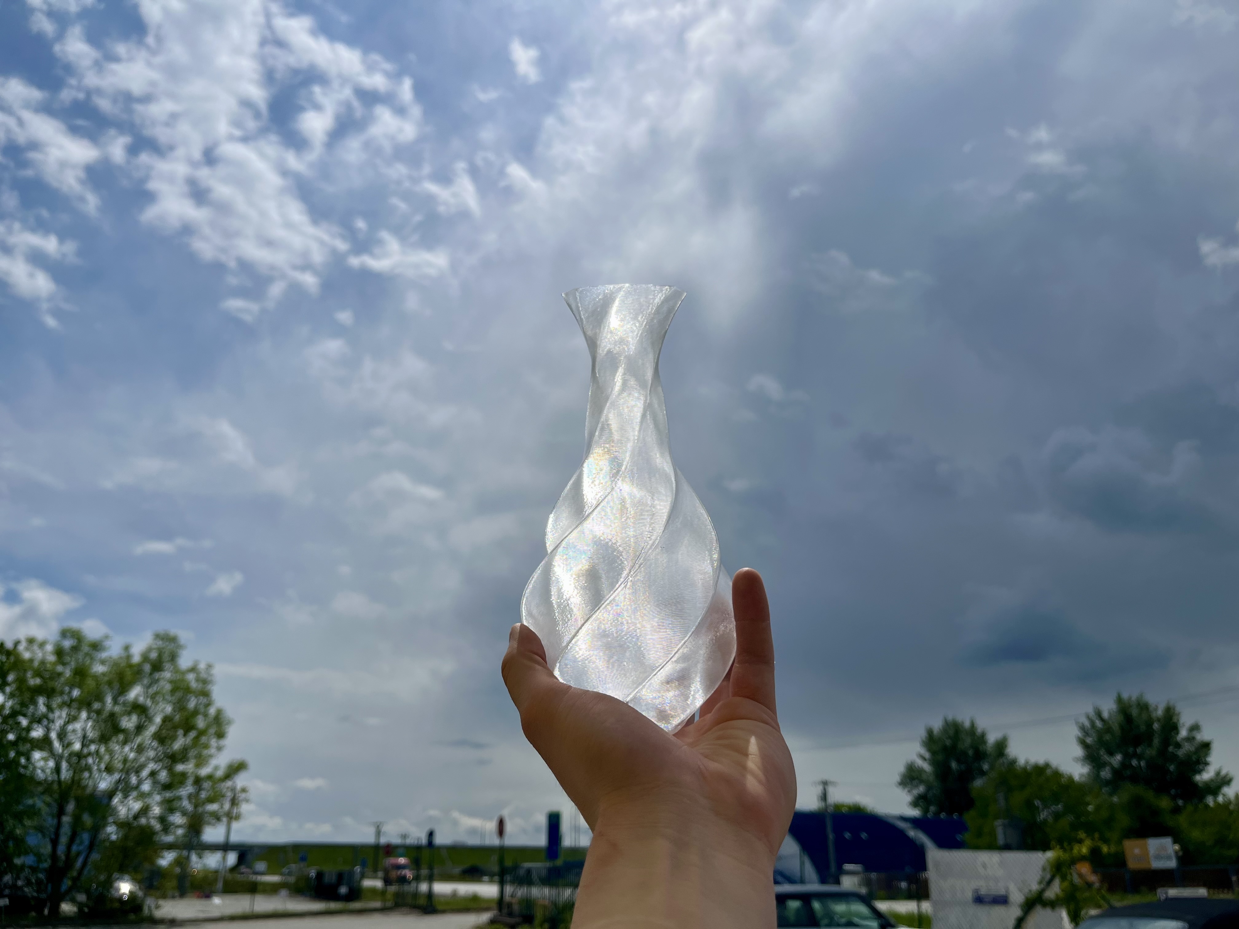 transparentní PETG vytištěný ve vase mode prosvícený sluncem — vrstvy vytváří iridescentní efekt