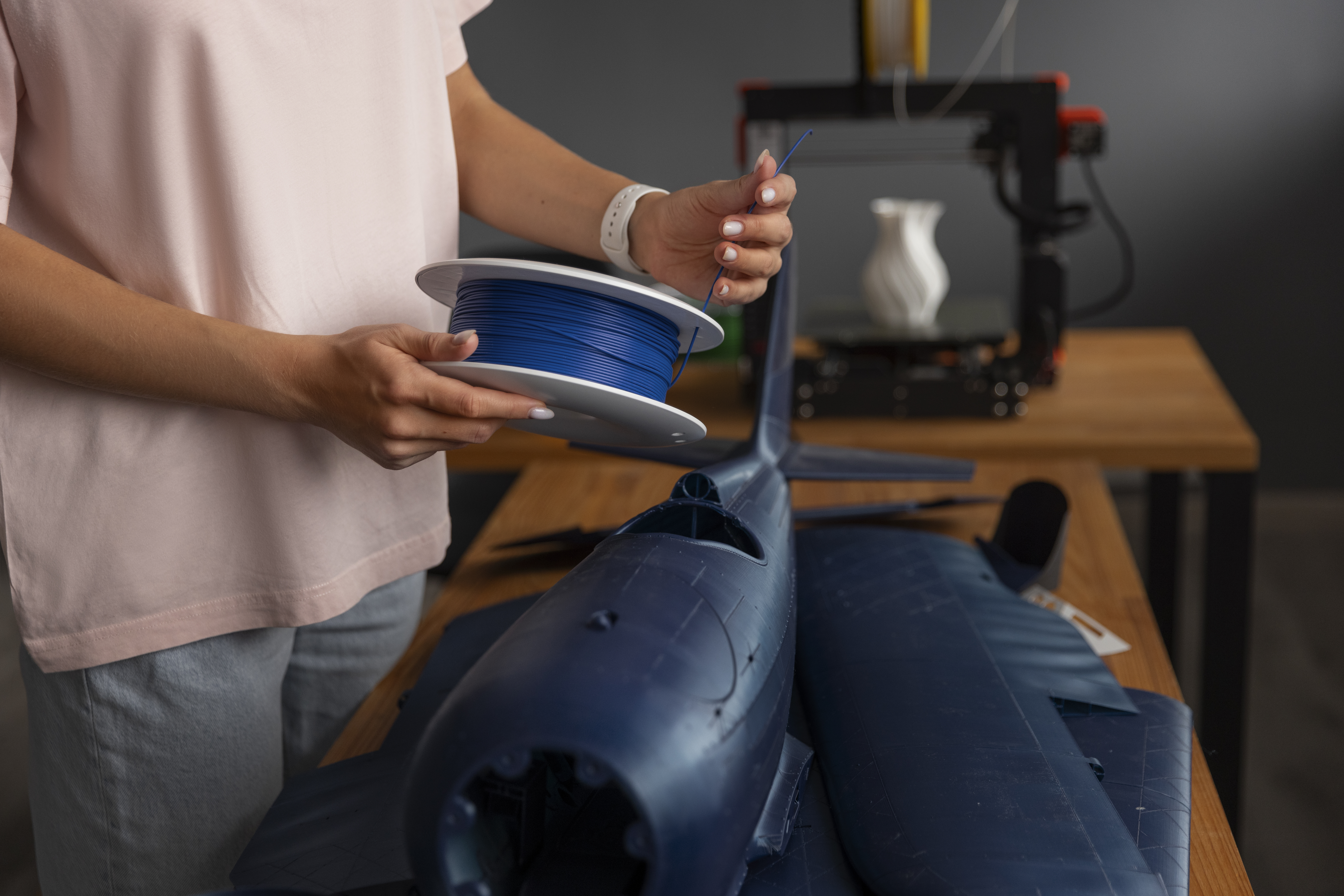 Ruka drží cívku filamentu u 3D tiskárny s velkým výtiskem