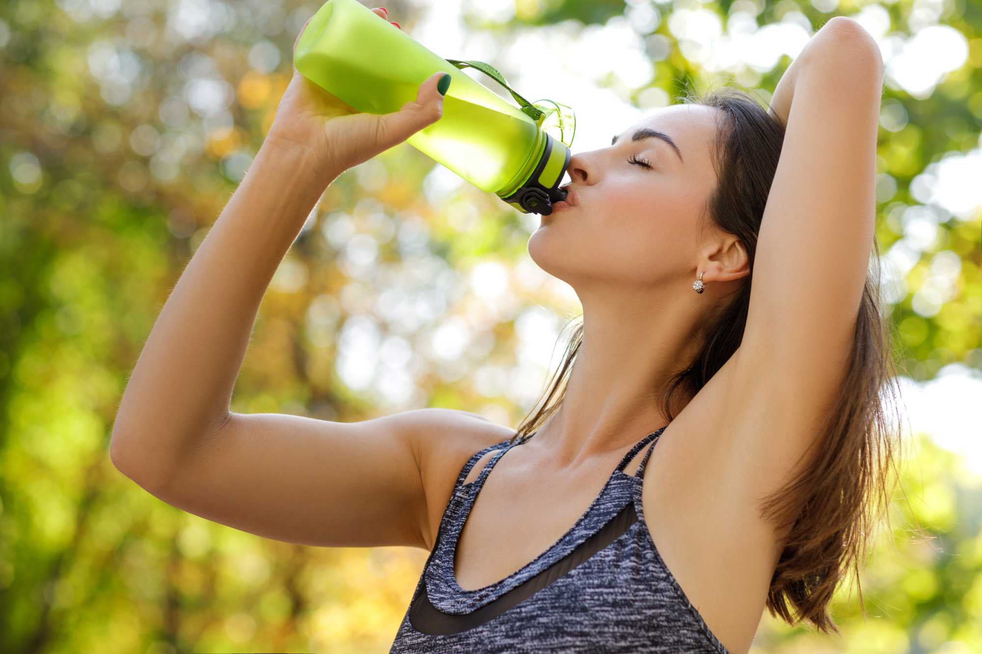 Žena pije čistú vodu z športovej fľaše
