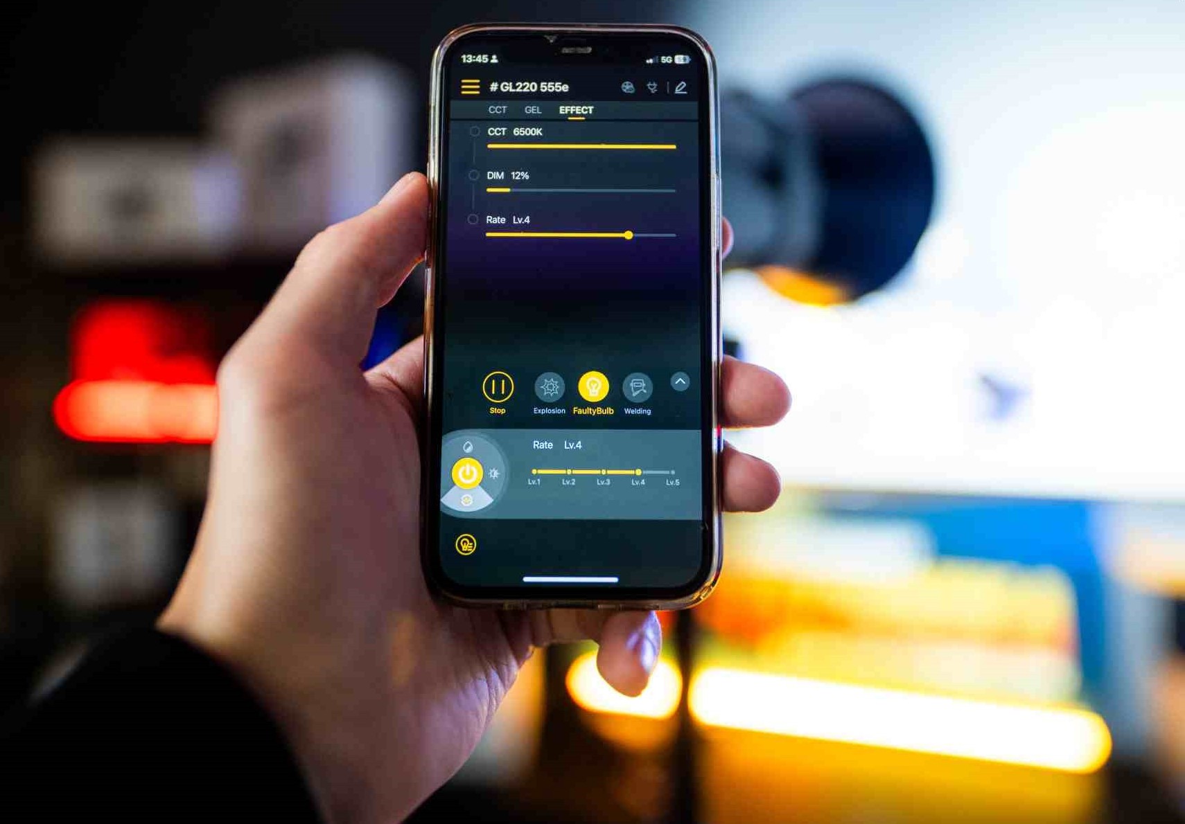 Ruka drží telefón s aplikáciou na ovládanie svetiel LENSBOT