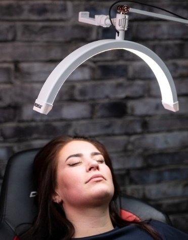 Klientka so zatvorenými očami pod lampou Redhead