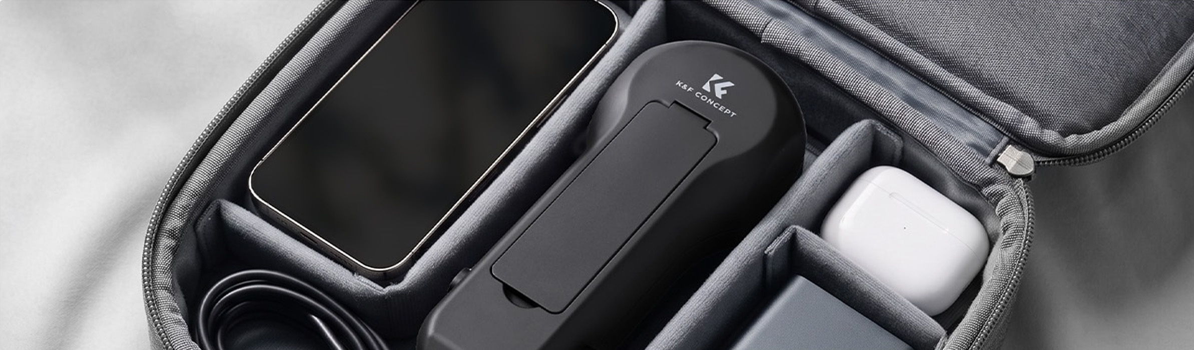 Kompaktní pouzdro K&F Concept uložené v brašně vedle telefonu a dalšího příslušenství