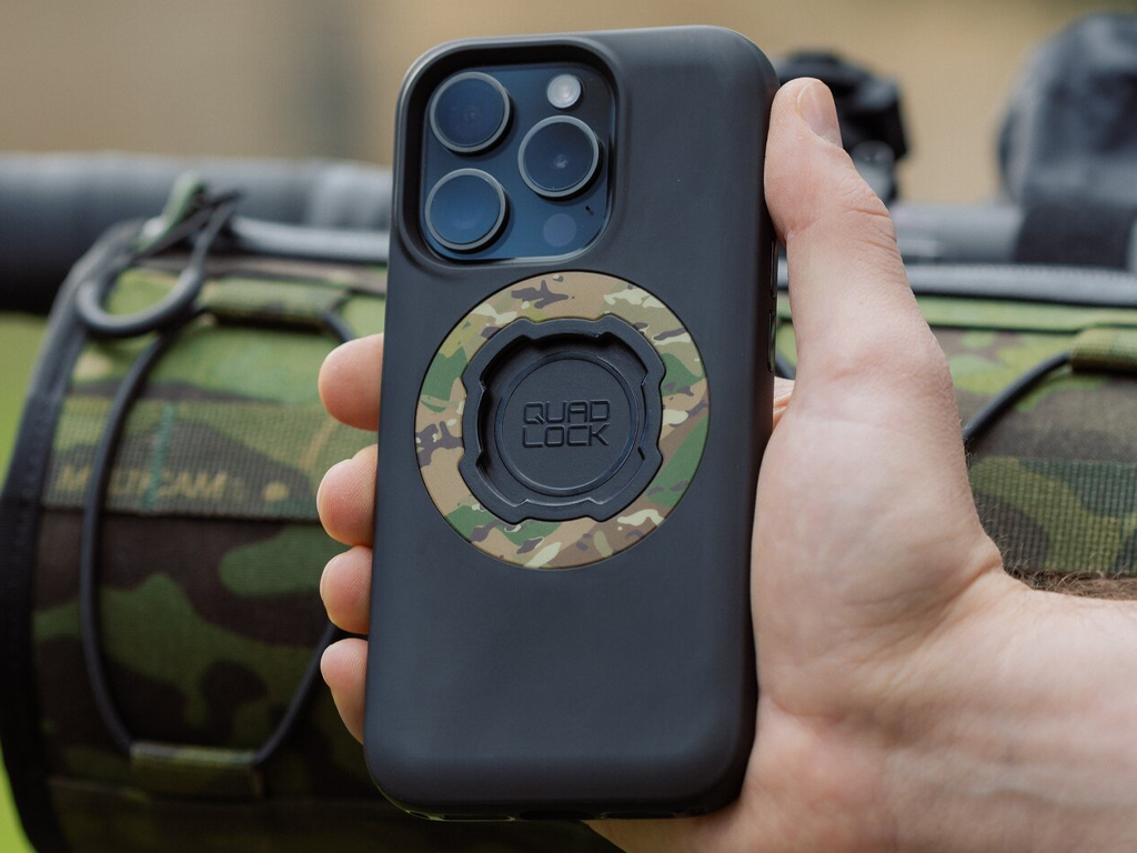 Maskáčový kroužek camo na pouzdře Quad Lock MAG v ruce, v pozadí maskáčová brašna