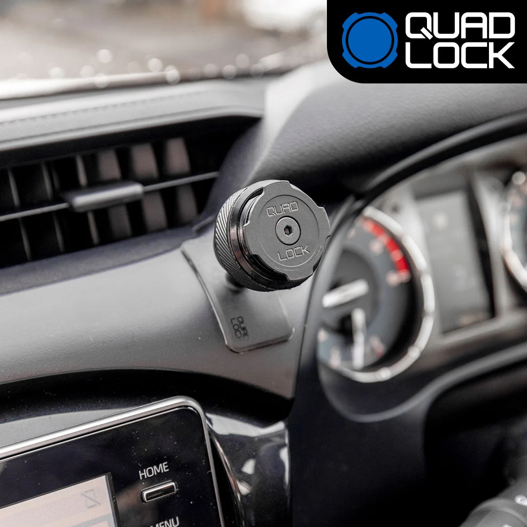 Lepicí držák Quad Lock Adhesive Dash/Console Mount nalepený na mírně zakřivené palubní desce vedle přístrojů a větrací mřížky