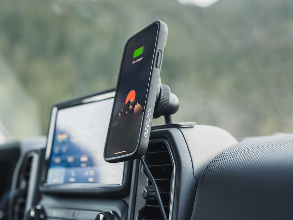 Nabíjející se telefon v pouzdře Quad Lock MAG (prodává se zvlášť) na bezdrátové nabíjecí hlavici MAG (prodává se zvlášť) a lepicím držáku na palubní desce