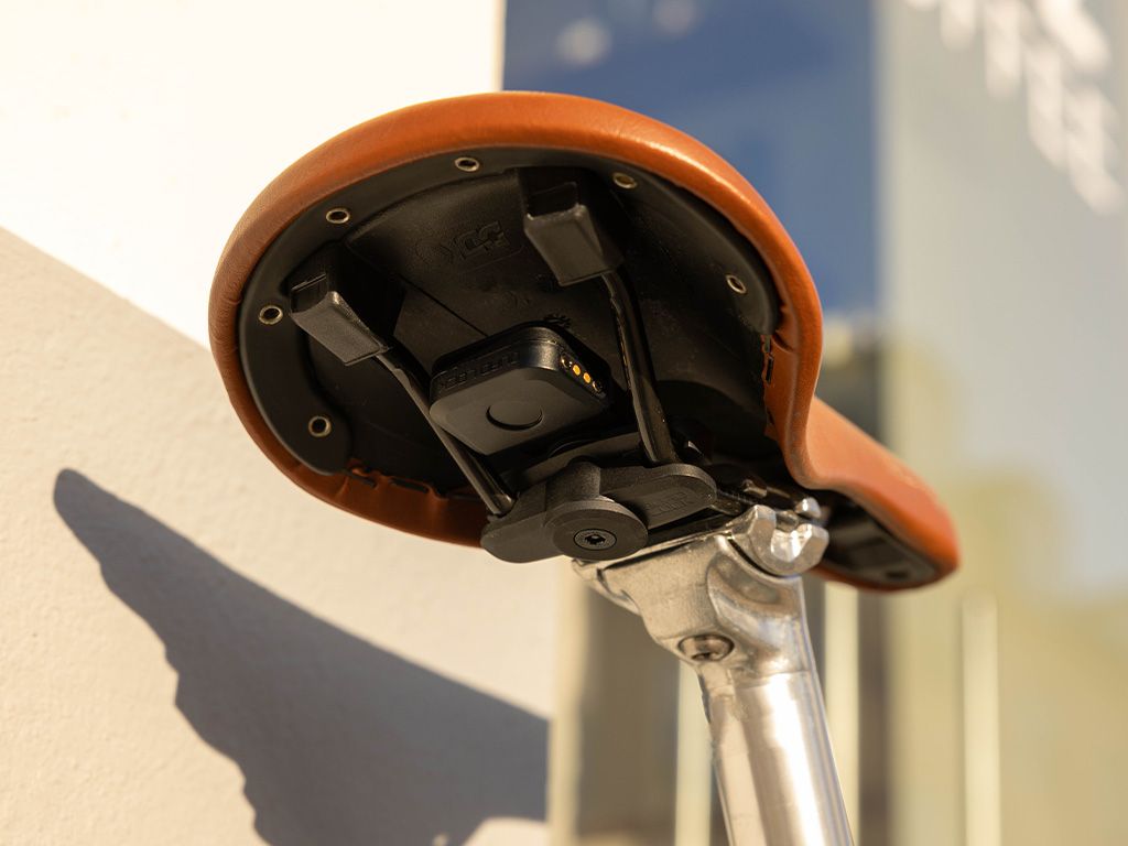 Alarm Quad Lock Bike Alarm and Finder (prodává se zvlášť) na adaptéru Quad Lock Saddle Rail Adaptor pod hnědým sedlem kola