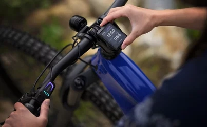 Ruka u displeje Bosch Kiox v držáku na řídítkách modrého horského elektrokola