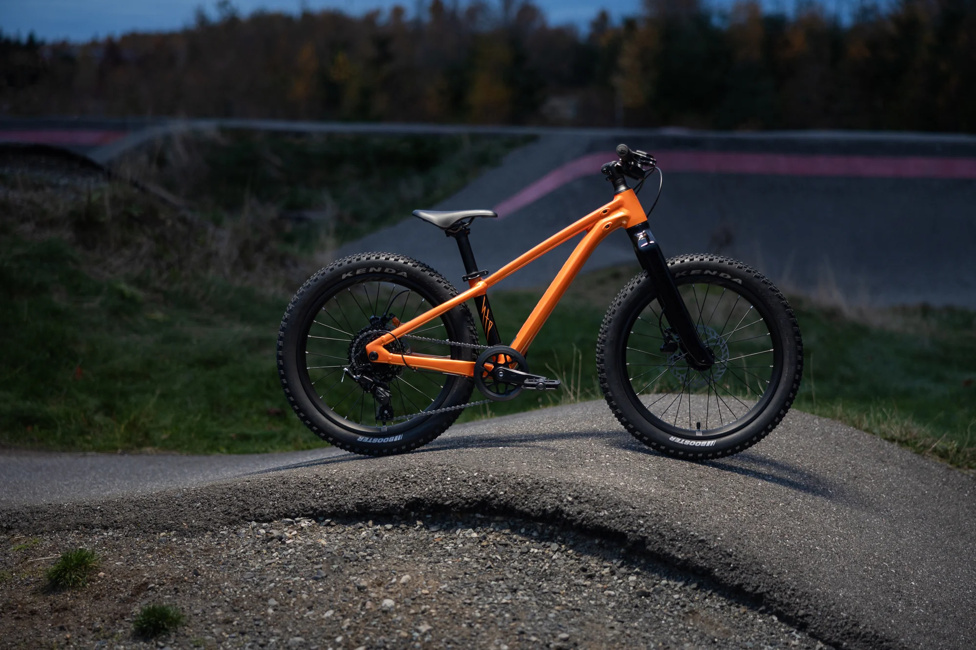 Giant STP 20 v barvě Metallic Orange stojí na zemním pumptracku za soumraku