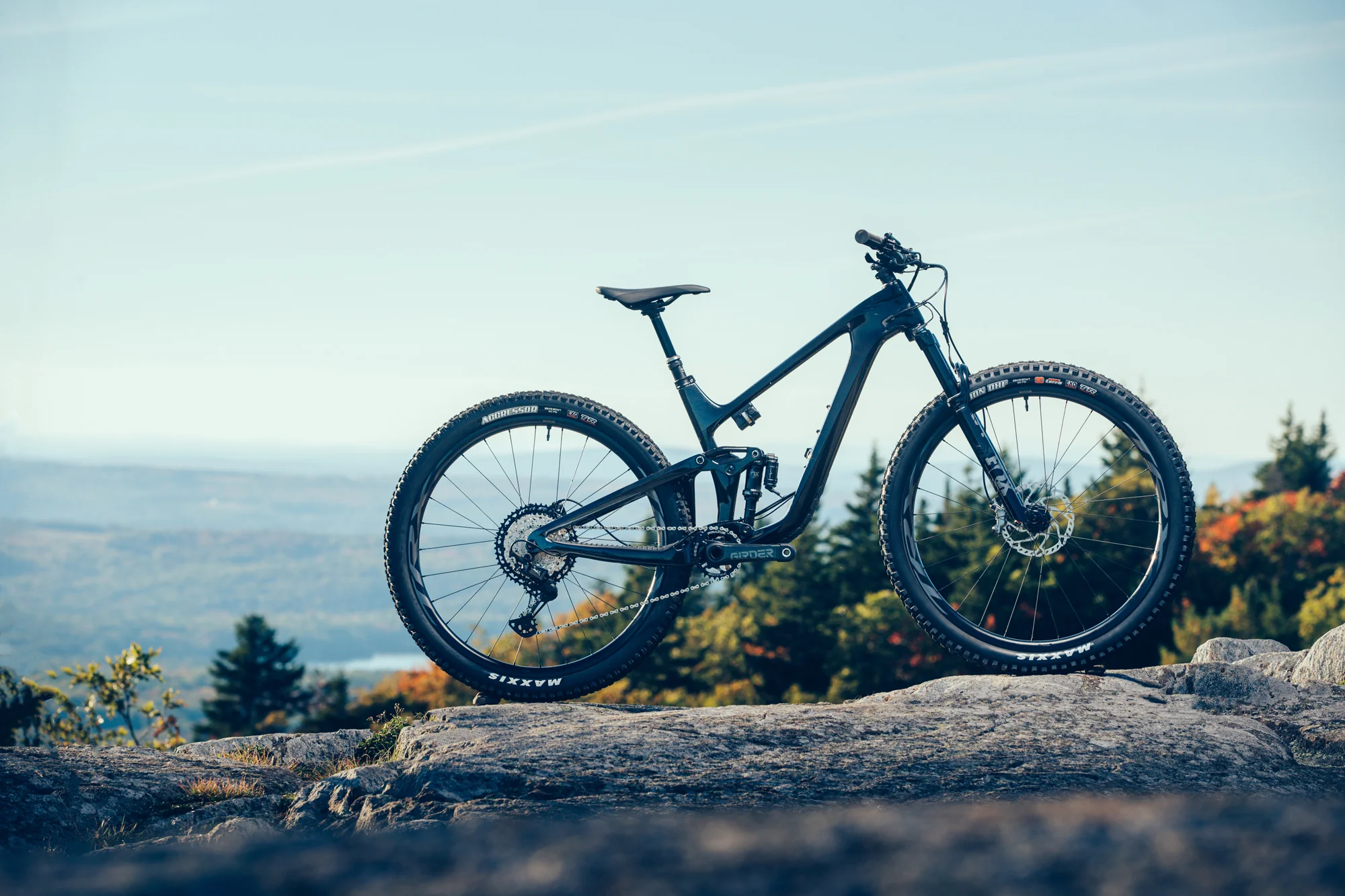 Tmavé karbonové kolo Giant Trance Advanced Pro 29 na skále nad krajinou