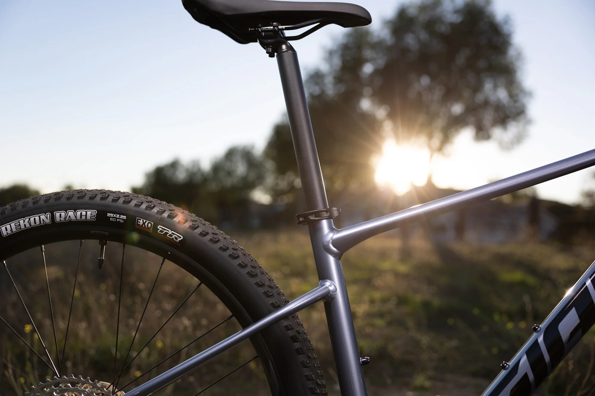 Sedlová trubka, sedlovka a plášť Maxxis Rekon Race na hliníkovém hardtailu Giant XTC SLR 29 2 při západu slunce