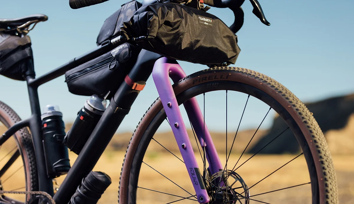 Detail karbonové vidlice Wilier Adlar s úchyty na nohách, v pozadí lahve a brašny na rámu